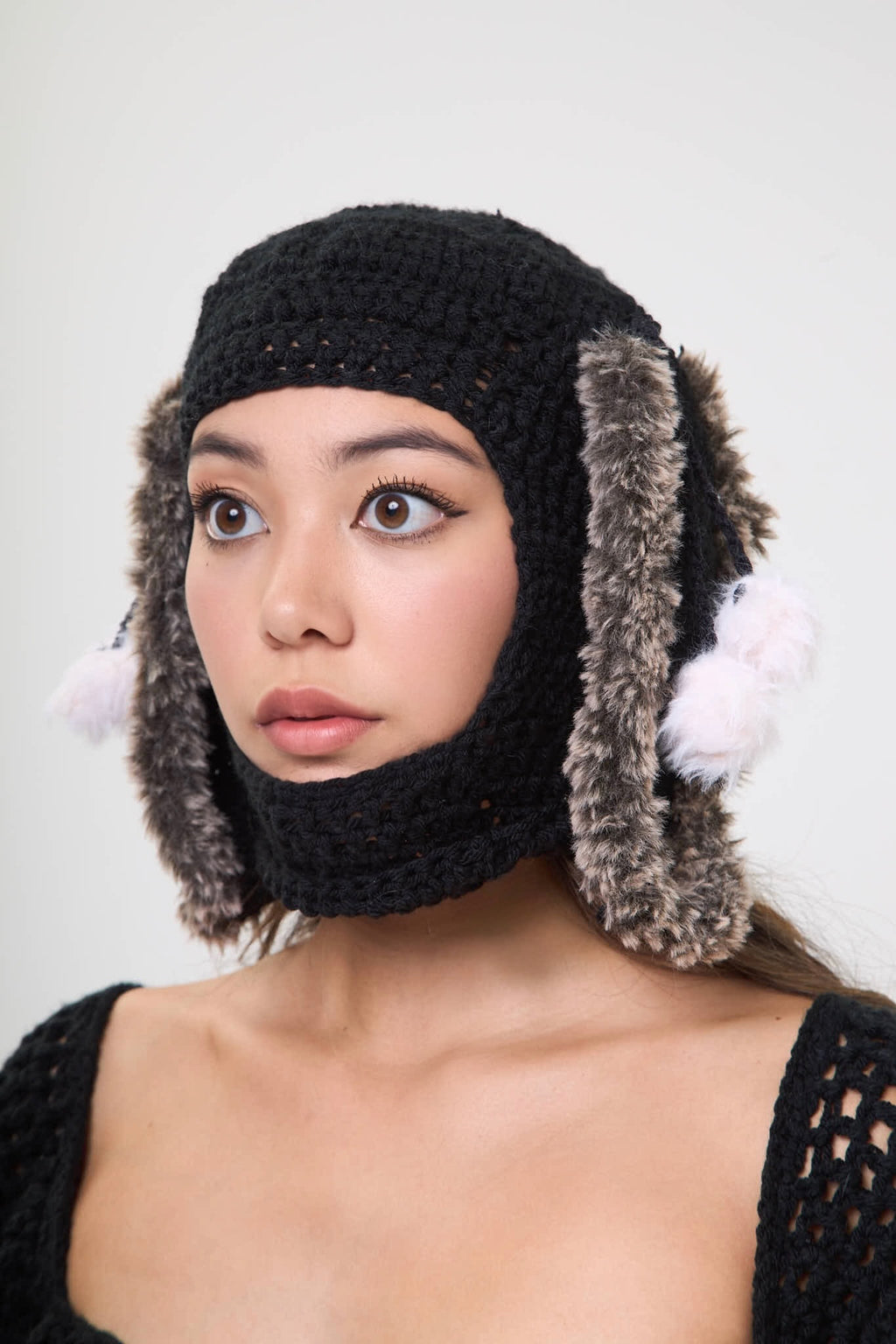 Model wearing the black Not Your Baby balaclava with fur ear details on a white background
