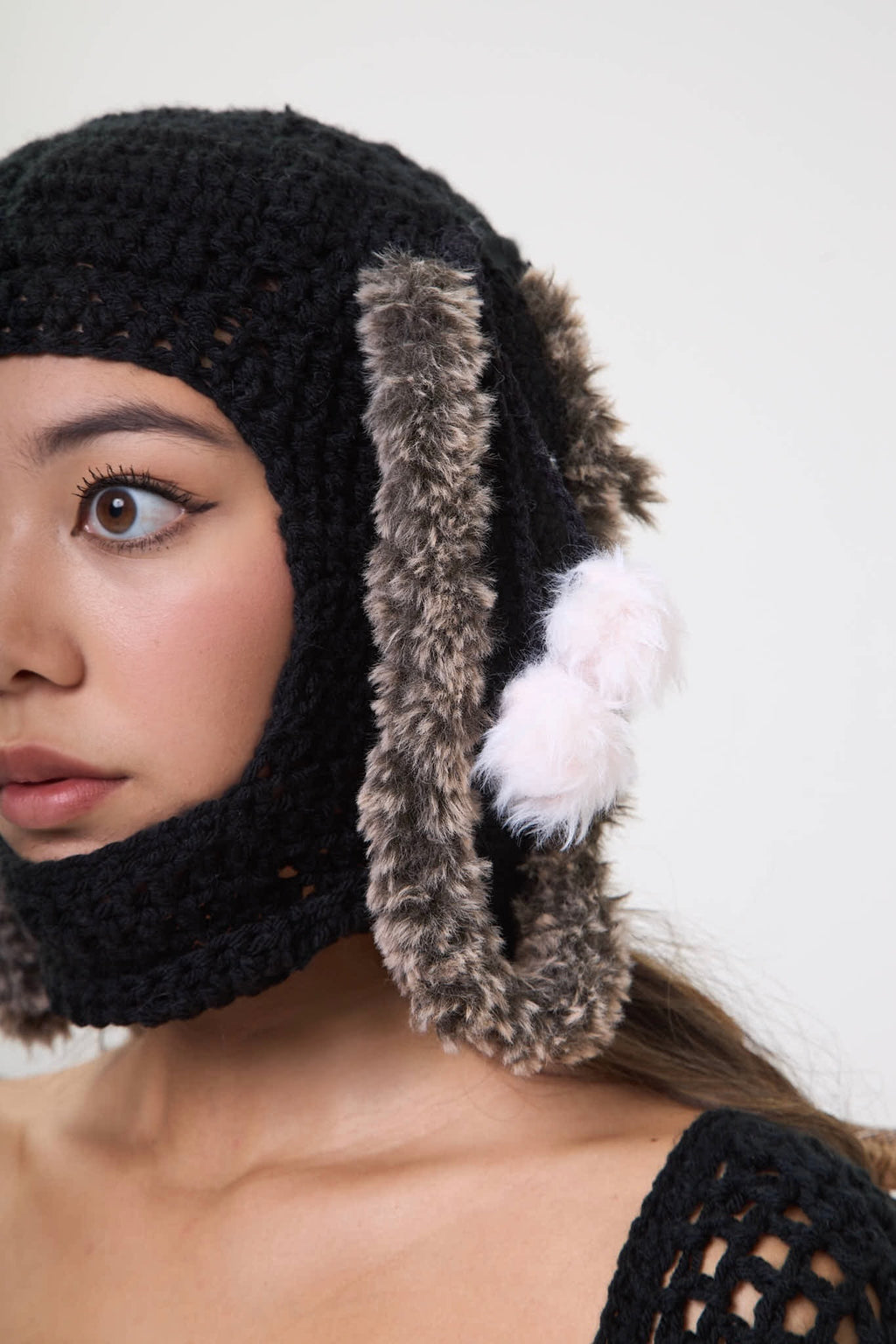 Side view of the black Not Your Baby balaclava showing fur trim and crochet texture