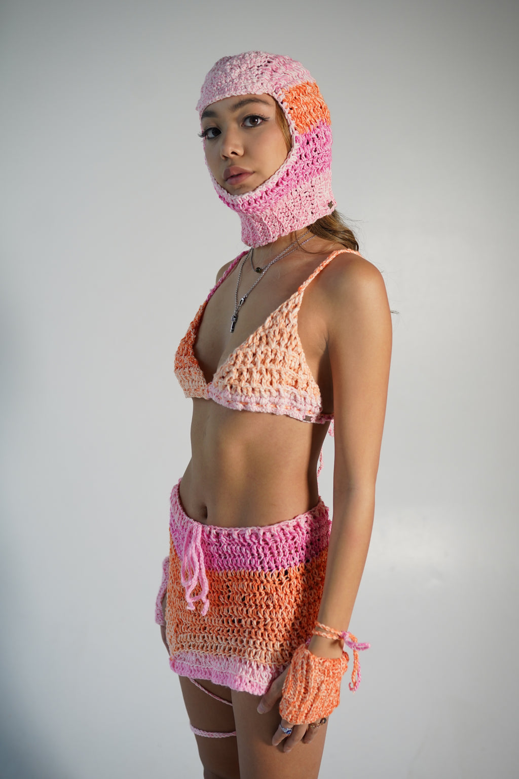 Model wearing sunset ombré crochet balaclava in orange and pink